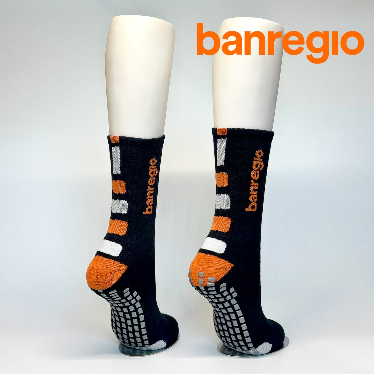 Calcetas personalizadas antidezlizantes color negro con detalles en blanco y naranja y el logo tejido de Banregio. Las regalaron a los empleados de banregio para promover el deporte en la empresa. 