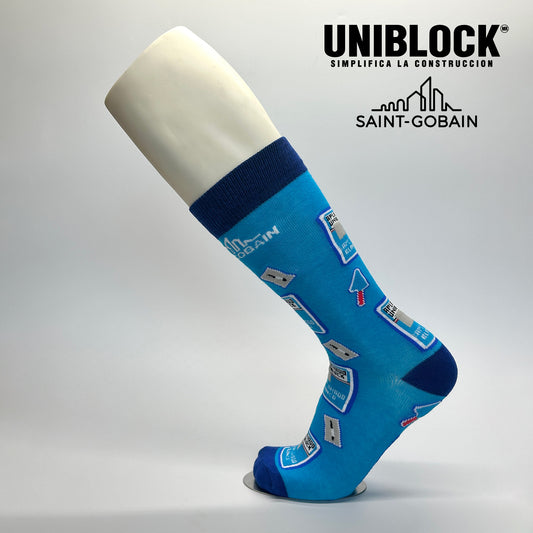 Calcetas personalizadas de vestir azules con iconos de construcción y el logo de UNIBLOCK y Sain-Gobain.
