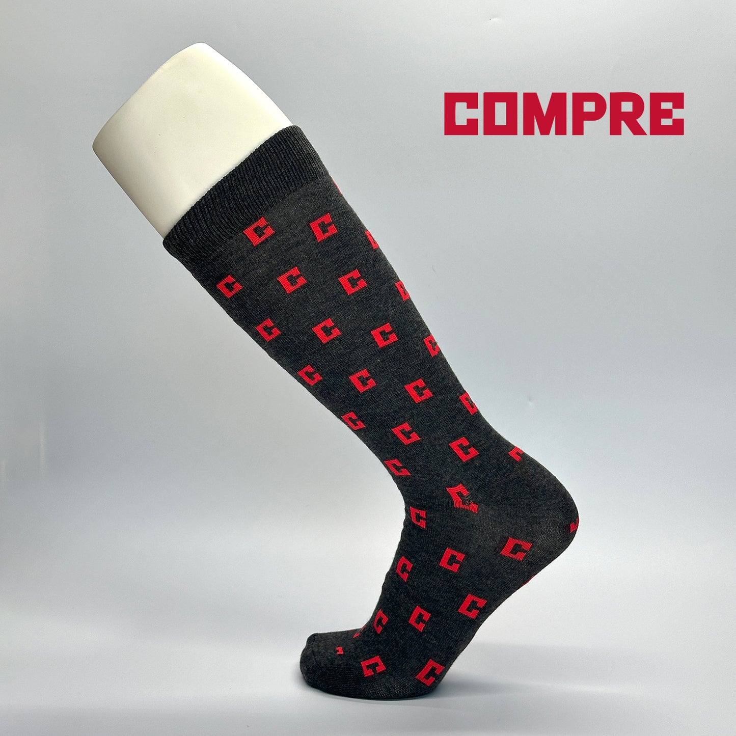 Calcetas personalizadas de vestir color gris con patrón de logo bordado de la empresa Compre. La empresa las utilizó para regalo del día del padre a sus empleados. 