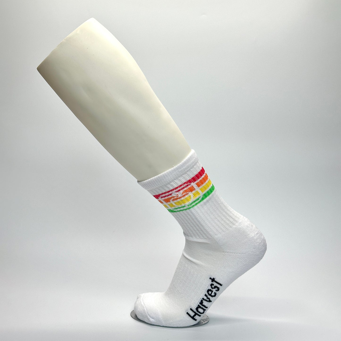 Calcetas personalizadas urbanas o semideportivas con fondo blanco y una franja de lineas en color orojo, naranja, amarillo y verde y al centro un icono de una manzana. 