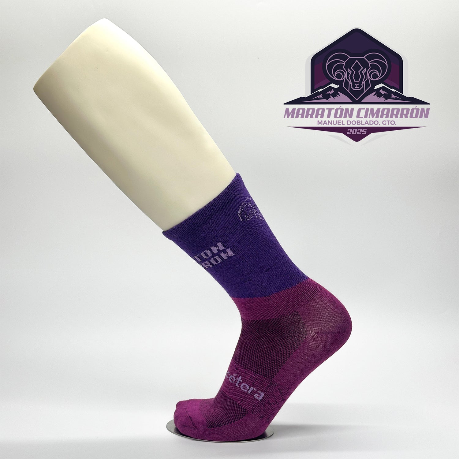 Calcetas personalizadas de ciclismo en dos tonos de morado, el icono de un cimarron que fue y el nombre de la carrera Maratón Cimarrón 2025. 