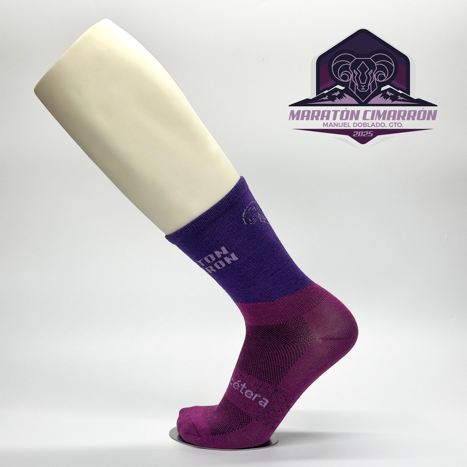 Calcetas personalizadas de ciclismo en dos tonos de morado, el icono de un cimarron que fue y el nombre de la carrera Maratón Cimarrón 2025. 