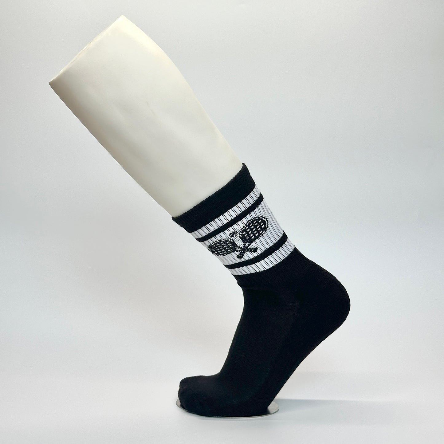 Calcetas personalizadas deportivas color negro conun dibujo de unas raquetas y pelote en blanco. Las calcetas las compraron para venderlas en unas canchas de paddel y son temáticas de paddel. 