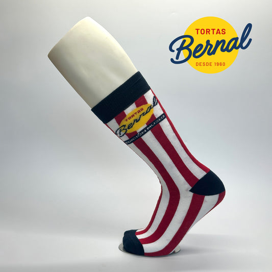 Calcetas personalizadas para la nueva sucursal de Tortas Bernal en la que festejan su aniversario. Las calcetas tienen un diseño de rayas verticales  blanco con rojo y el logo original de las tortas en el laterales así como los detalles de elastico, punta y talón en azul marino. 