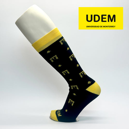 Calcetas personalizadas tradicionales para la UDEM. El diseño es color negro con el icono de la campana típico de la universidad. La calceta se vende en la tienda oficial de la universidad.