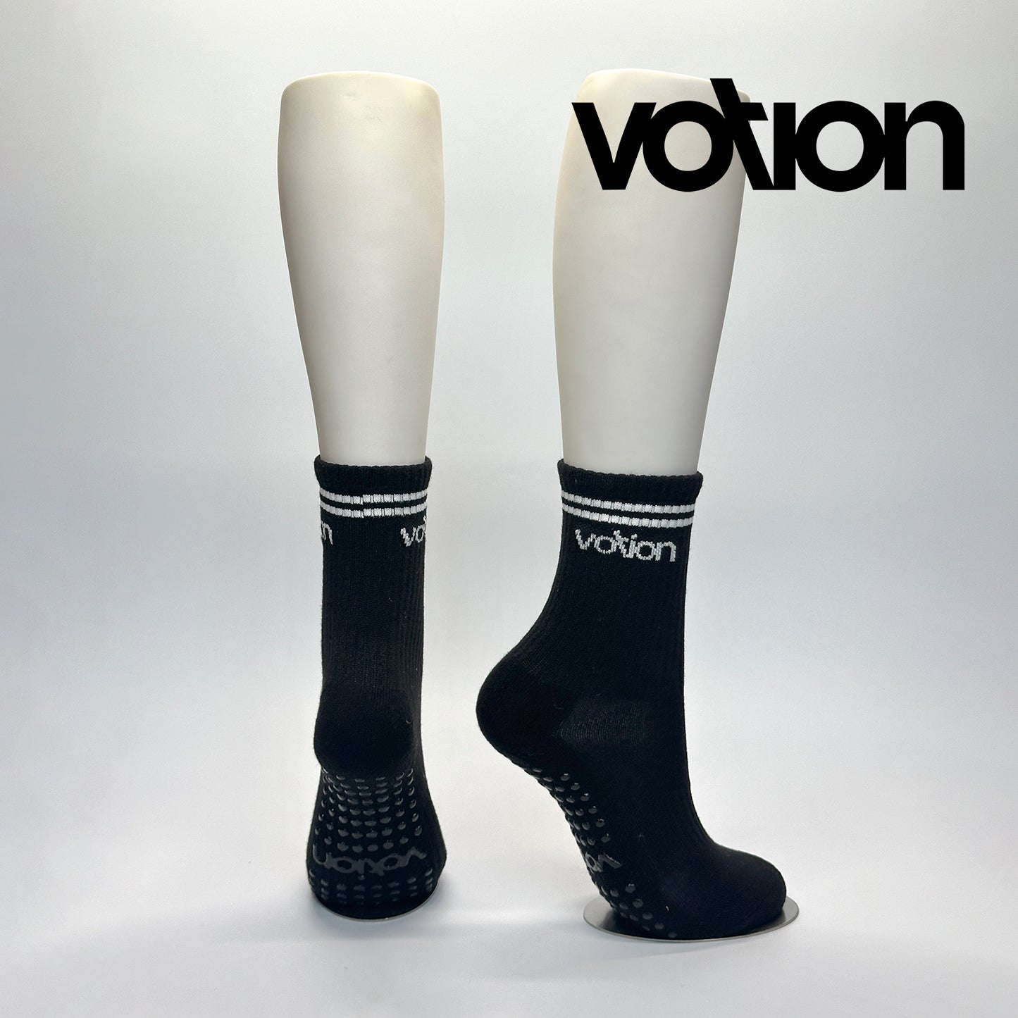 Calcetas personalizadas antiderrapante con suela personalizada con el logo de Votion. La calceta es negra con dos franjas blancas y el logo de Votion. Las compró el emprendedor de votion para vender en sus nuevas tiendas.