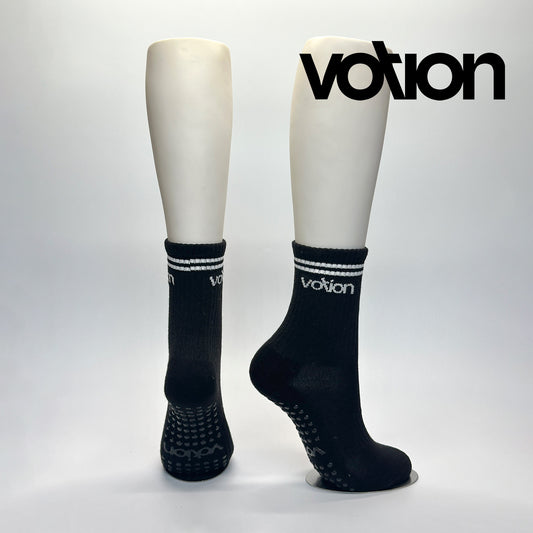 Calcetas personalizadas antiderrapante con suela personalizada con el logo de Votion. La calceta es negra con dos franjas blancas y el logo de Votion. Las compró el emprendedor de votion para vender en sus nuevas tiendas.